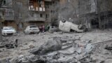 Residents stand near their apartment building and vehicles damaged during a Russian missile strike during Russia's attack on Ukraine, in Kharkiv, Ukraine, Dec. 8, 2023. 