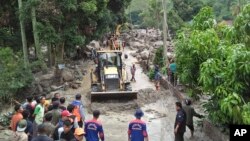 Rescue workers use heavy machines to clear a road from rock and mud following a landslide in Simangulampe village, North Sumatra, Indonesia, Dec. 2, 2023. 