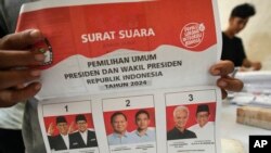 Seorang petugas memegang surat suara untuk pemilihan presiden tanggal 14 Februari yang memperlihatkan para kandidat, dari kiri, Anies Baswedan- Muhaimin Iskandar, Prabowo Subianto-Gibran Rakabuming Raka, Ganjar Pranowo-Mahfud MD, di Tangerang, 10 Januari 2024. (AP/Tatan Syuflana)