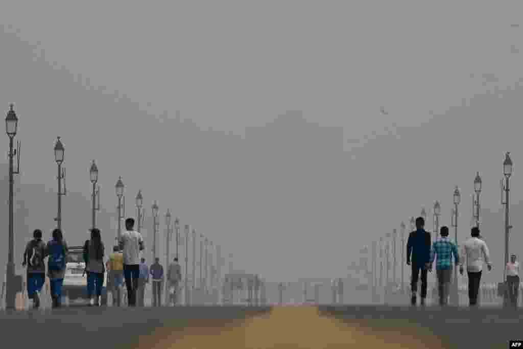 People walk along the Kartavya Path near India Gate amid heavy smog conditions in New Delhi. Schools were shut across India&#39;s capital on November 3 as a noxious grey smog engulfed the megacity. (Photo by ARUN THAKUR / AFP)