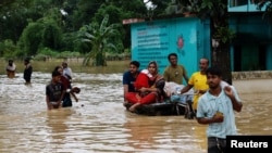 FILE - People move a cart with a woman and a child through a flooded street, amid severe flooding in the Fazilpur area of Feni, Bangladesh, Aug. 26, 2024. 