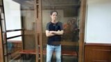 ນັກຂ່າວ Wall Street Journal ທ່ານ ທ່ານເອແວັນ ເກີ​ສໂກວິຈ ຢຶນຢູ່ໃນຄັອກແກ້ວ ຢູ່ໃນສານນະຄອນຫລວງມົສກູ ປະເທດຣັດເຊຍ ວັນທີ 22 ມິຖຸນາ 2023