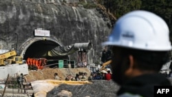 A rescue worker stands near an entrance to a tunnel under construction, days after a portion of it collapsed, in the Uttarkashi district of India's Uttarakhand state, Nov. 23, 2023.