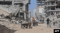 গাজা ভূখণ্ডের দক্ষিণাঞ্চলে খান ইউনিসে ইসরাইলের বোমায় বিধ্বস্ত বাড়িঘরের মধ্য দিয়ে নিজেদের জিনিসপত্র নিয়ে যাচ্ছে বাস্তুচ্যুত ফিলিস্তিনিরা। ৬ মার্চ, ২০২৪।