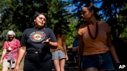 FILE - Serina Fast Horse of the Sicangu Lakota and Blackfeet Tribes, left, talks with Jacy Bowles, of Xicana and Diné descent, as they walk during the 2023 Tribal Climate Camp on the Olympic Peninsula near Port Angeles, Washington, Aug. 16, 2023.
