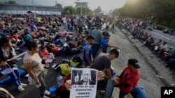 Un migrante sostiene una fotografía del presidente mexicano Andrés Manuel López Obrador que dice en español: "Las vidas de los migrantes también importan" mientras su caravana se detiene para bloquear la carretera en Huixtla, México, el miércoles 8 de noviembre de 2023. 