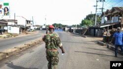 A soldier with the Sierra Leonean military police greets and man along an empty road in Freetown, Nov. 26, 2023.
