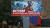 FILE - A local resident walks past a billboard encouraging men to join a Russian battalion amid Moscow's war on Ukraine, in Melitopol, Russian-occupied Ukraine, Nov. 27, 2022. Three Russian officers were reportedly killed in an attack Saturday on a local military headquarters.