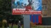 Seorang warga lokal berjalan melewati sebuah papan iklan yang berisi seruan kepada para pria untuk bergabung dengan pasukan Rusia di tengah perang Rusia-Ukraina, di Melitopol, pada 27 November 2022. (Foto: Reuters/Alexander Ermochenko)