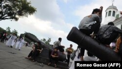 Anak-anak muda terlihat duduk di atas meriam berusia seabad di luar Museum Fatahillah, Jakarta. Belanda mengatakan akan menyerahkan kembali ratusan artefak era kolonial ke Indonesia dan Sri Lanka. (Foto: AFP/Romeo Gacad)