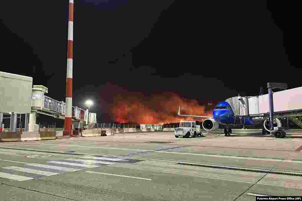 Plumes of fire and smoke cover the hills surrounding Palermo&#39;s airport, Sicily, Italy, late Monday night, July 24, 2023, causing its shutdown and leaving planes trapped on the tarmac.&nbsp;The airport reopened on July 25 only for departing planes.&nbsp;