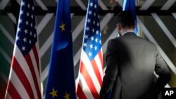 Работник ги прилагодува знамињата на САД и ЕУ пред пристигнувањето на шефот за надворешна политика на ЕУ и американскиот државен секретар за време на министерскиот состанок на Советот за енергетика ЕУ-САД во Европскиот совет во Брисел, 4 април 2023 година