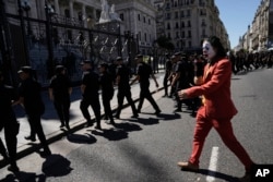 A protester in a Joker costume imitates a TV reporter as police leave an area near Congress at the end of a protest against economic and labor reforms proposed by the Argentine government, during a national strike in Buenos Aires, Jan. 24, 2024.