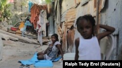 (FILE) A woman and a girl sit at the New Church of God of Deliverance camp for displaced people in Port-au-Prince, Haiti.