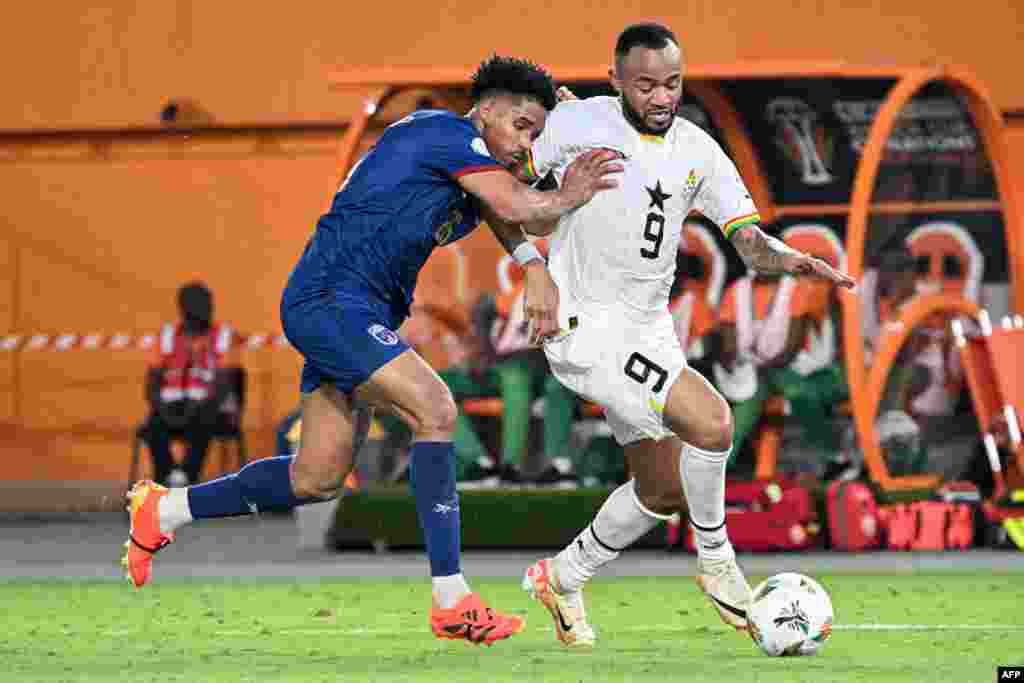 O cabo-verdiano Kevin Pina (L) disputa a bola com o avançado ganês Jordan Ayew (9) durante o jogo de futebol do grupo B da Taça das Nações Africanas (CAN) 2024, em Abidjan, a 14 de janeiro de 2024. (Foto de SIA KAMBOU / AFP)