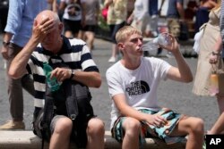 Turis-turis sedang minum di tengah gelombang panas di Roma, Italia, dengan suhu mencapai 40 derajat Celsius di banyak kota di Italia, Sabtu, 8 Juli 2023. (Foto: Gregorio Borgia/AP Photo)