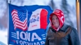 FILE - A man stands next to a flag that reading "Iowa for Trump" in Urbandale, Iowa, Jan. 11, 2024. Voters in the state are participating in caucuses on Jan. 15, 2024, that launch the Republican presidential nomination process.