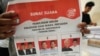 2024年1月10日，一名工人在印尼坦格朗準備分發選舉後勤物資期間，手持2月14日總統選舉的選票，展示候選人及其競選夥伴。（美聯社照片）