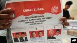 2024年1月10日，一名工人在印尼坦格朗準備分發選舉後勤物資期間，手持2月14日總統選舉的選票，展示候選人及其競選夥伴。（美聯社照片）