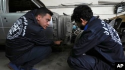 Khosro Dahaghin, left, talks with a worker at his workshop while restoring a Cadillac Seville, in Roudehen, some 30 miles (45 kilometers) east of Tehran, Iran, June 7, 2023.