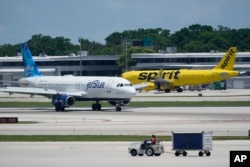 FILE - Pesawat Airbus A320 JetBlue Airways (kiri), melewati sebuah pesawat Airbus A320 Spirit Airlines saat meluncur di landasan pacu di Bandara Internasional Fort Lauderdale-Hollywood di Fort Lauderdale, Florida, 7 Juli 2022.(Wilfredo Lee/AP)