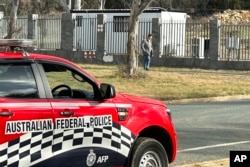 A man walks along a fence that surrounds a a building on the grounds of a proposed new Russian embassy near the Australian Parliament in Canberra where an Australian Federal Police officer observes from his vehicle, June 23, 2023.