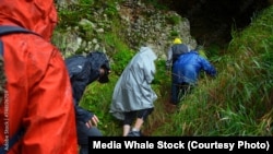 Hikers enter cave to get out of the rain. (Adobe Stock Photo/by Media Whale Stock)