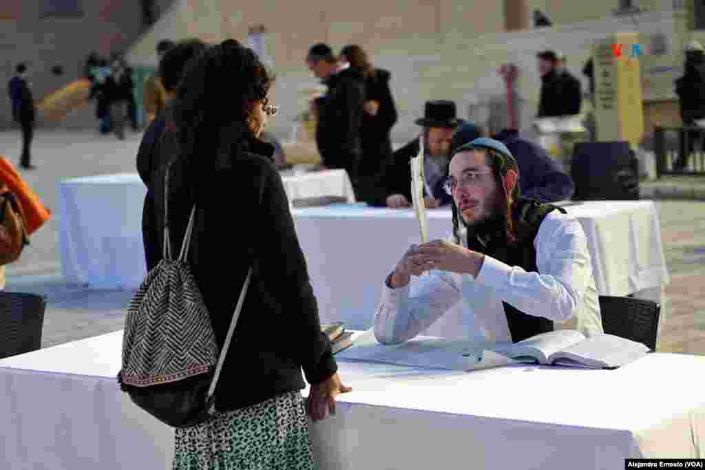 Un escriba conversa con una mujer antes de plasmar sus deseos en un rollo de la Torá durante la ceremonia en homenaje a los secuestrados y fallecidos durante la guerra entre Israel y Hamás.