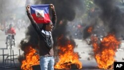 A demonstrator holds up a Haitian flag during protests demanding the resignation of Prime Minister Ariel Henry in Port-au-Prince, Haiti, March 1, 2024.