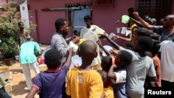 FILE - People hold pots as volunteers distribute food in Omdurman, Sudan, Sept. 3, 2023.