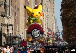 Handlers guide the Pikachu and Eevee balloon along Central Park West during the Macy's Thanksgiving Day parade, Nov. 23, 2023, in New York.