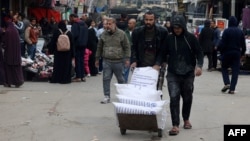 Displaced Palestinians push a barrow loaded with bags of flour they received from the United Nations Relief and Works Agency for Palestine Refugees in Rafah in the southern Gaza Strip on Jan. 28, 2024,