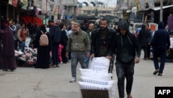 FILE - Displaced Palestinians push a barrow loaded with bags of flour they received from the U.N. Relief and Works Agency for Palestine Refugees in Rafah in the southern Gaza Strip, Jan. 28, 2024,