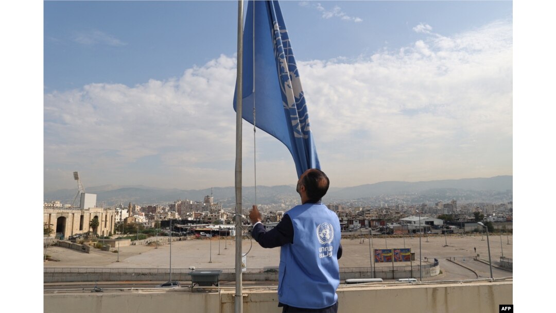 An employee at the United Nations Relief and Works Agency (UNRWA) for supporting Palestinians lowers the U.N. flag on the roof of the organization's regional offices in the Lebanese capital of Beirut, Nov. 13, 2023.