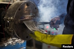 Seorang karyawan pabrik TileGreen tengah memproduksi ubin ramah lingkungan yang terbuat dari berbagai jenis plastik dan limbah, 15 Maret 2023. (Hadeer Mahmoud/REUTERS)