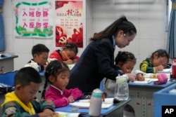 Seorang guru membantu siswanya menulis alfabet di kelas satu di Shangri-La Key Boarding School di daerah Dabpa, Prefektur Kardze, provinsi Sichuan, China, 5 September 2023. (AP/Andy Wong)