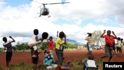 FILE - Children in Mulanje look on as a military helicopter carry doctors and medical supplies to Muloza on the border with Mozambique which are cut off after the tropical Cyclone Freddy outside Blantyre, Malawi, March 18, 2023.