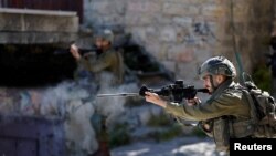 Seorang tentara Israel menembakkan peluru karet ke arah warga Palestina saat bentrokan setelah kematian tahanan Palestina Khader Adnan yang melakukan aksi mogok makan di penjara Israel, di Hebron, Tepi Barat 2 Mei 2023. (REUTERS/Mussa Issa Qawasma)