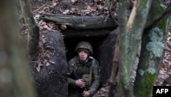 Seorang prajurit Ukraina sedang mengintai dari tempat perlindungan bawah tanah di garis depan dekat Kota Bakhmut di wilayah Donetsk Ukraina selama invasi Rusia ke Ukraina, 18 November 2023. (Foto: Anatolii Stepanov/AFP)