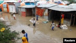 Somali children wade through flood waters outside their makeshift shelters following heavy rains at the Al Hidaya camp for the internally displaced people on the outskirts of Mogadishu, Somalia, Nov. 6, 2023. 