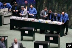 Para pegawai parlemen mengatur pemungutan suara anggota parlemen untuk calon menteri Presiden Iran Masoud Pezeshkian dalam sidang terbuka parlemen di Teheran, Iran, Rabu, 21 Agustus 2024. (Vahid Salemi/AP)