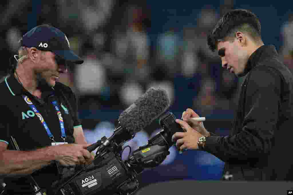 Carlos Alcaraz of Spain signs his autograph on a TV camera after defeating Richard Gasquet of France in their first round match at the Australian Open tennis championships at Melbourne Park, Melbourne.