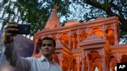 A person takes selfie in front of a replica of the Lord Ram temple in Ayodhya, which is on display outside India's ruling Bharatiya Janata Party office, in Mumbai, India, Jan. 16, 2024.