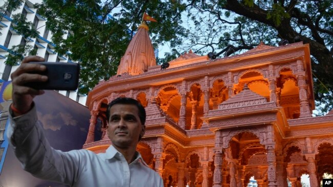 A person takes selfie in front of a replica of the Lord Ram temple in Ayodhya, which is on display outside India's ruling Bharatiya Janata Party office, in Mumbai, India, Jan. 16, 2024.