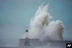 Waves crash over Newhaven Lighthouse and the harbor wall in Newhaven, southern England, Nov. 2, 2023.