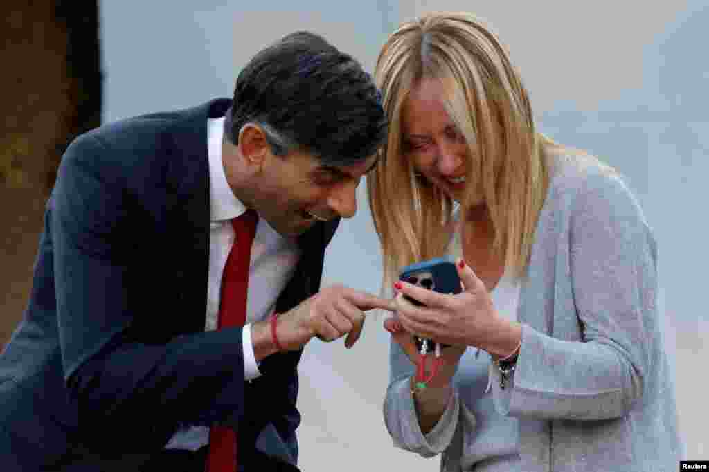 Britain's Prime Minister Rishi Sunak and Italy's Prime Minister Giorgia Meloni react ahead of the social dinner during the NATO summit, at the Presidential Palace in Vilnius, Lithuania, July 11, 2023. 