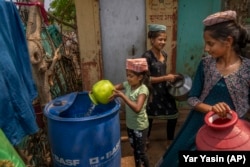 FILE - A girl empties a pot of water into a plastic container outside her home after collecting it from a nearby well in Telamwadi, northeast of Mumbai, India, Saturday, May 6, 2023. AP Photo/Dar Yasin)