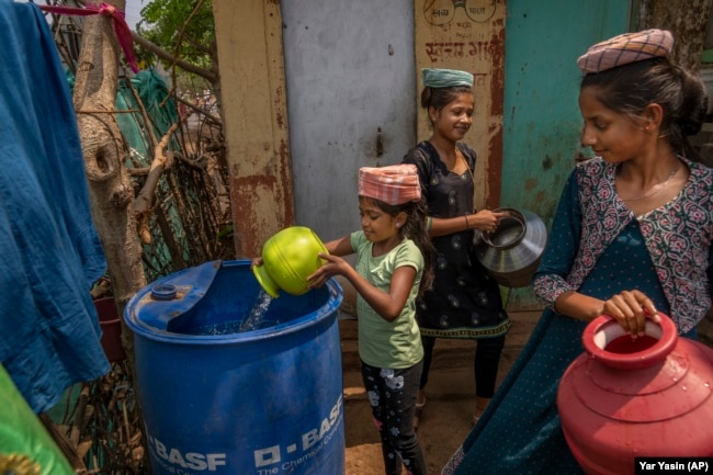 FILE - A girl empties a pot of water into a plastic container outside her home after collecting it from a nearby well in Telamwadi, northeast of Mumbai, India, Saturday, May 6, 2023. AP Photo/Dar Yasin)