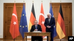 Turkey's President Recep Tayyip Erdogan, left, signs the guest book beside German President Frank-Walter Steinmeier, right, during Erdogan's visit in Berlin, Germany, Nov. 17, 2023.
