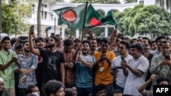 Para pelajar memegang bendera nasional Bangladesh saat mereka berunjuk rasa menuntut pengunduran diri Ketua Mahkamah Agung Obaidul Hassan, di depan Mahkamah Agung di Dhaka pada 10 Agustus 2024. (Foto: AFP)